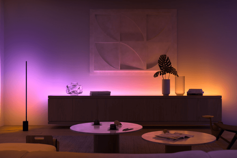 Man sieht die Philips Hue Signe Stehlampe, wie sie eine Zimmerecke beleuchtet.